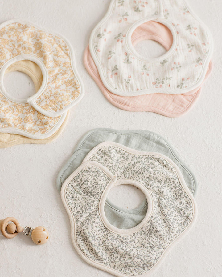 three different sets of bibs in a flower shape. one of them is a sage green print and the other has strawberry print