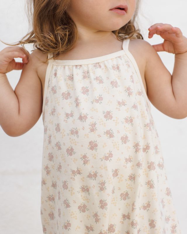 Child wearing a floral romper against a plain background