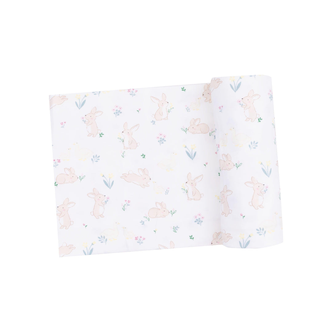 baby swaddle with bunnies and ducks printed on it. white ground color. tiny bunnies and ducks and tiny flowers on it as well 