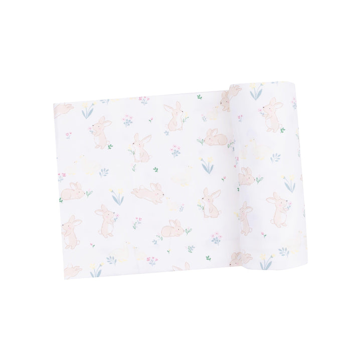 baby swaddle with bunnies and ducks printed on it. white ground color. tiny bunnies and ducks and tiny flowers on it as well 