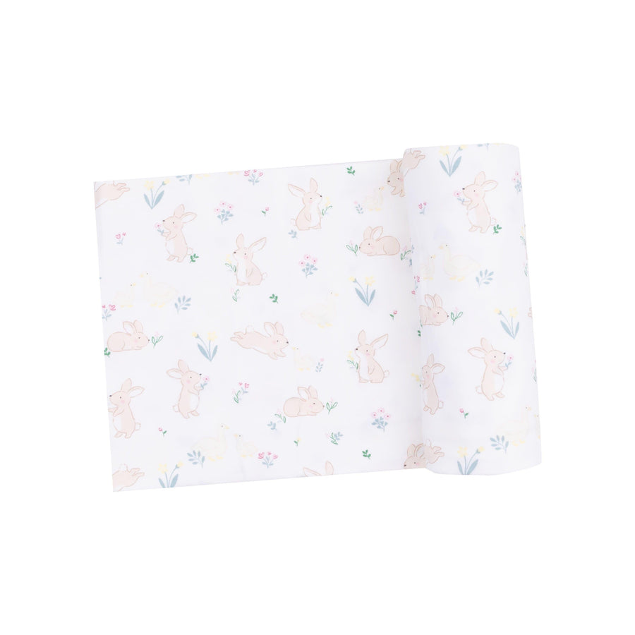baby swaddle with bunnies and ducks printed on it. white ground color. tiny bunnies and ducks and tiny flowers on it as well 