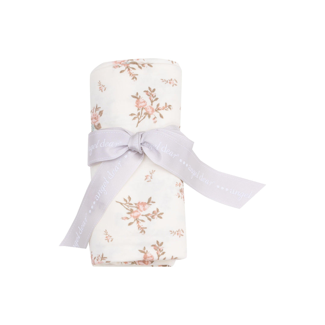 baby swaddle rolled up and tied with a ribbon. showing how the swaddle comes packaged. swaddle with vinatge pink rosebuds all over. 
