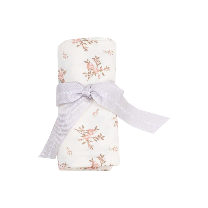 baby swaddle rolled up and tied with a ribbon. showing how the swaddle comes packaged. swaddle with vinatge pink rosebuds all over. 