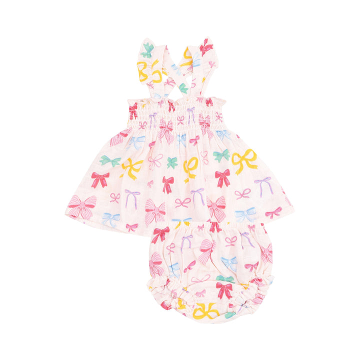 baby girl dress with smocking at the top and sleeves that criss cross. white base with multi colored bows all over: pink, yellow, purple. 