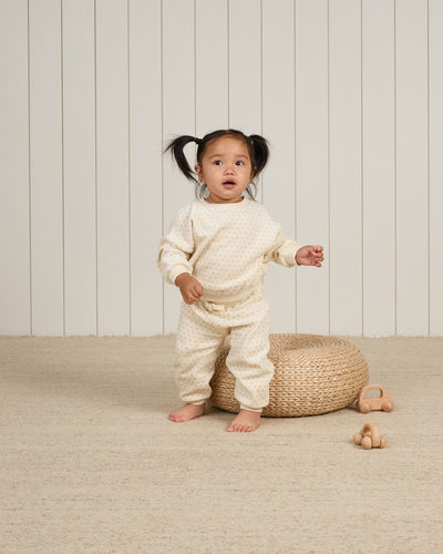 little girl modeling the beige polka dot sweastuit