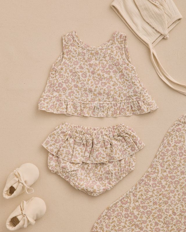 Baby outfit set with floral top and bloomers on a beige background