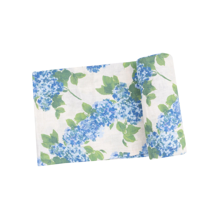 baby swaddle with white base and vibrant blue hydrengeas and big green leaves