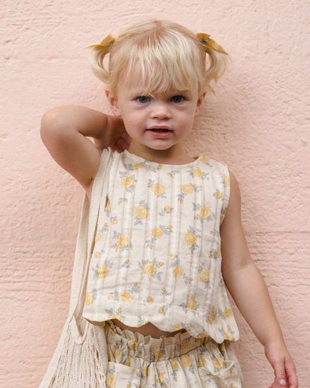 Young girl in a floral dress standing against a pink textured wall