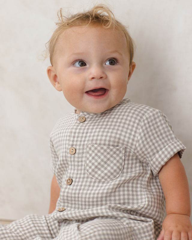 Baby wearing a sage checkered outfit with a plain background