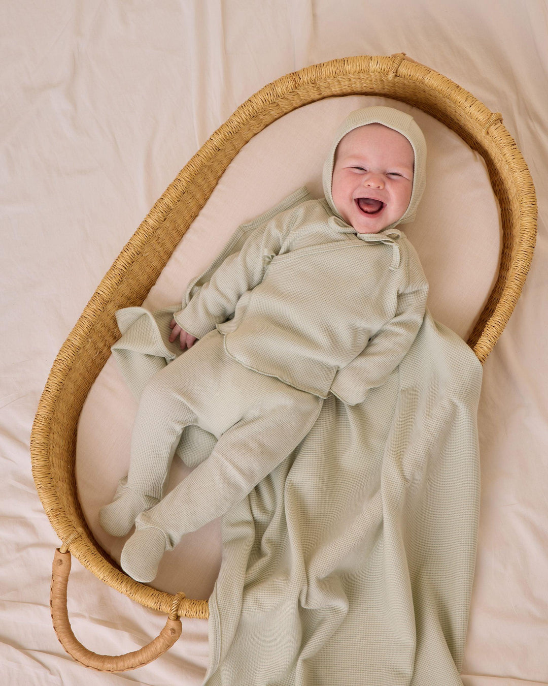 baby wearing a take home set and bonnet in a mint green