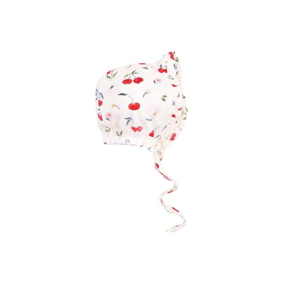 white baby bonnet with jred cherries and small white flowers on it. ruffles around the edge. 
