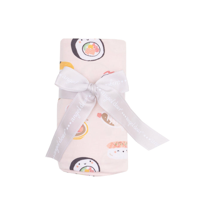 this baby swaddle is pink with sushi printed all over it. this picture shows the swaddle all rolled up and tied with a ribbon the way it comes packaged. 