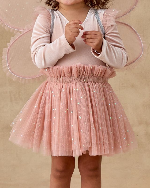 Child wearing a pink tulle skirt with a plain background