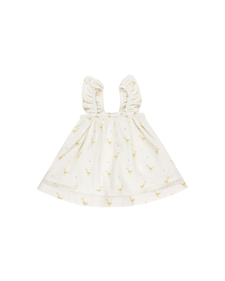 beige dress with yellow geese printed on it. sleeveless ruffles for sleeves. 