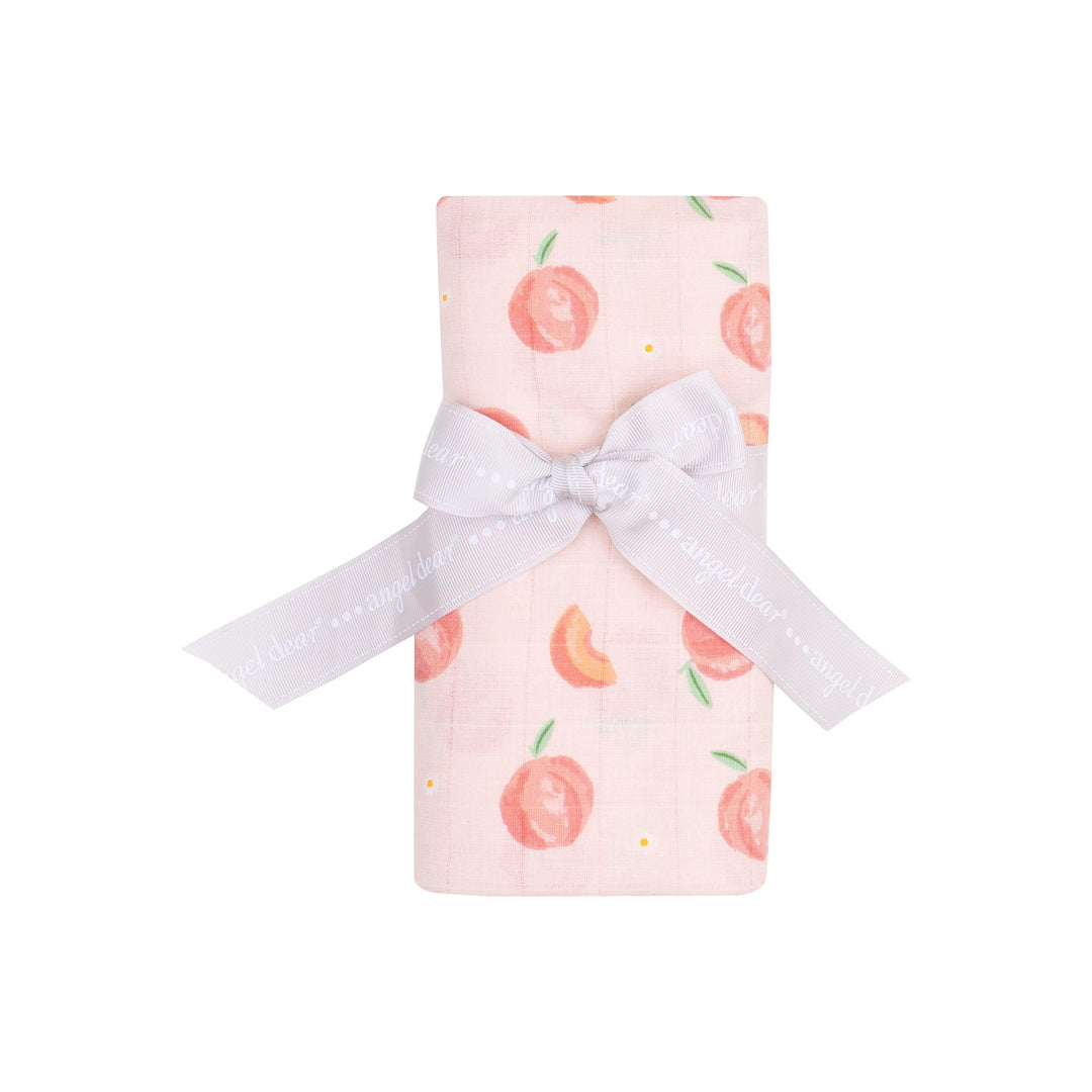 baby swaddle rolled and tied with a ribbon. the swaddle has peaches on it in a light pink/peach base color. 