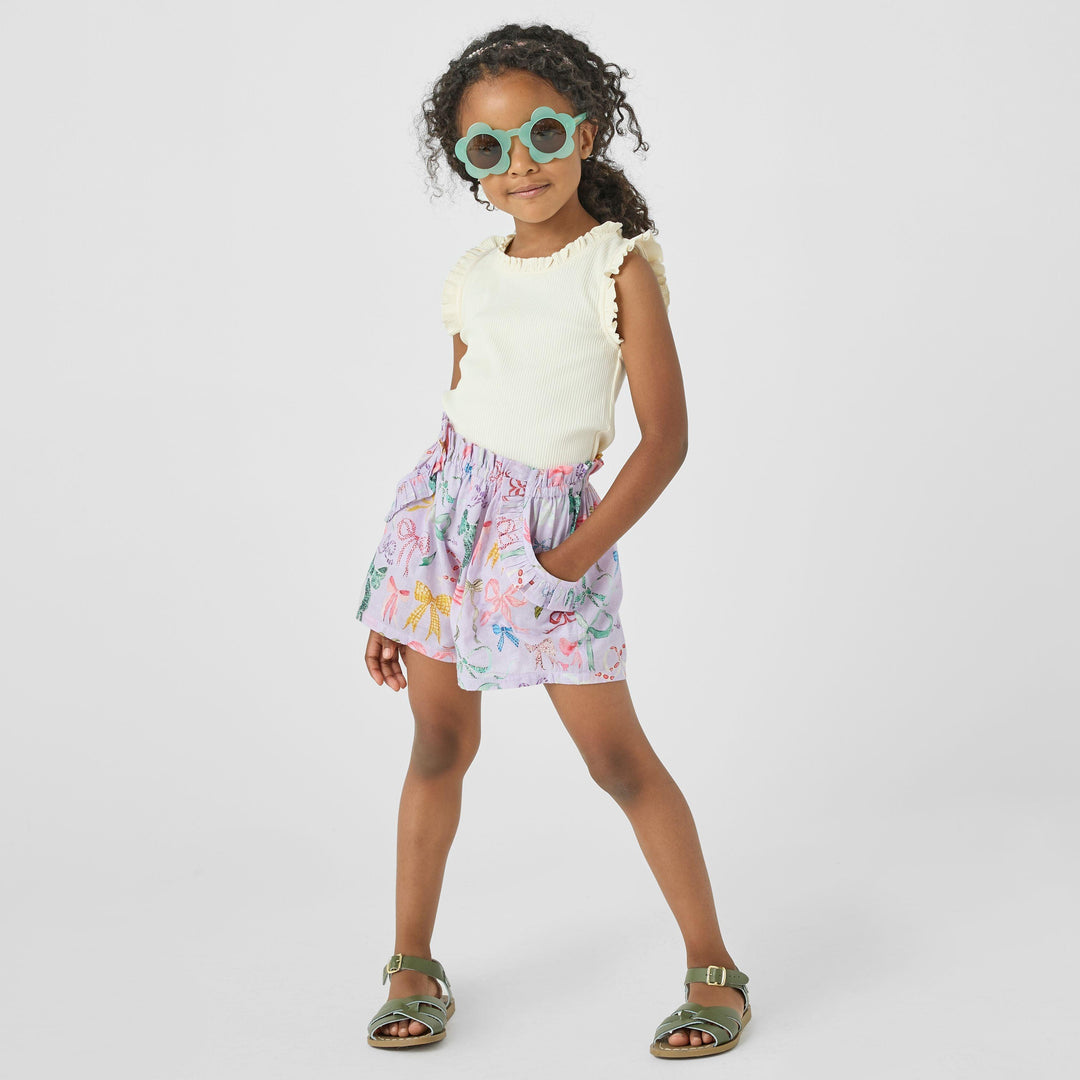 little girl wearing a tank and the lavender high waisted shorts with different color bows all over it. 