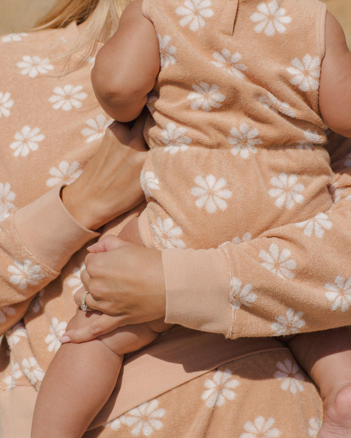 baby wearing the cinch playsuit in grapefruit color with daisy print all over. 