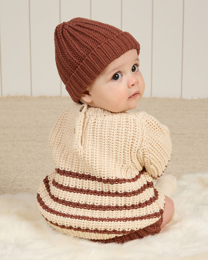 Baby modeling the chunky beige knit with cranberry stripes on the bottom. 