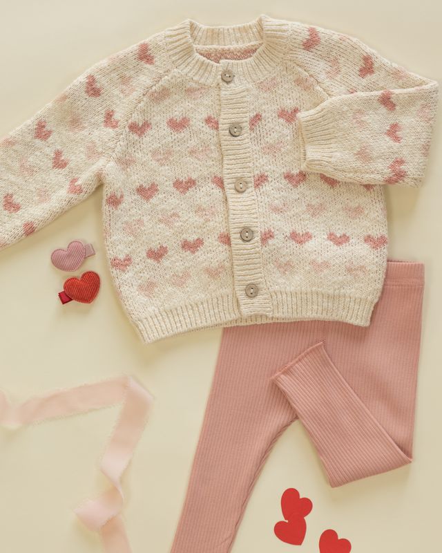 Baby sweater and leggings set with heart pattern on a light background