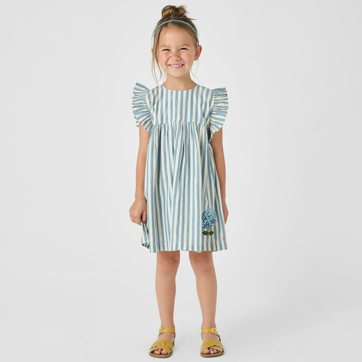 little girl modeling the blue and white striped dress with ruffles at the sleeves and blue hydrengea embroidered at the bottom left corner of the dress. 