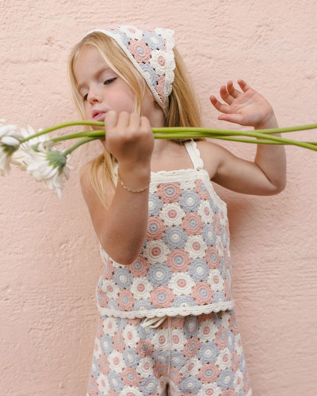 young girl wearing a two piece crochet outfit with floral shapes. in pastel flowers. 