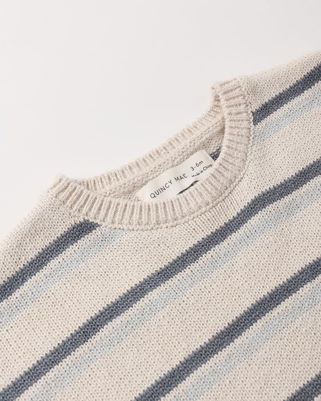 Close-up of a striped sweater with a visible brand label on a light background