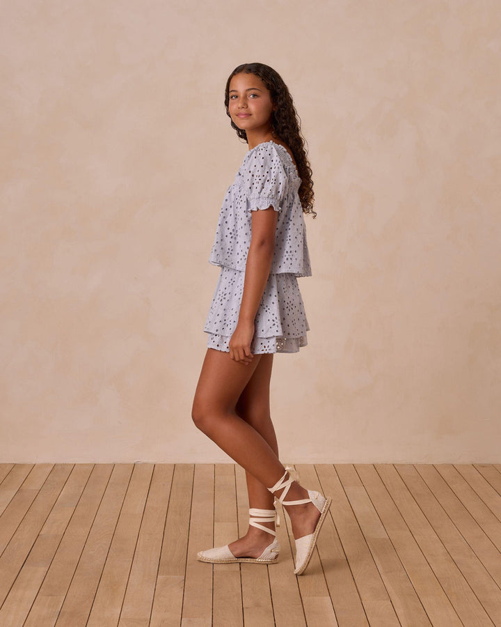 sideview of the blue eyelet top and skirt. puff sleeve and two tiers of the eyelet skirt 