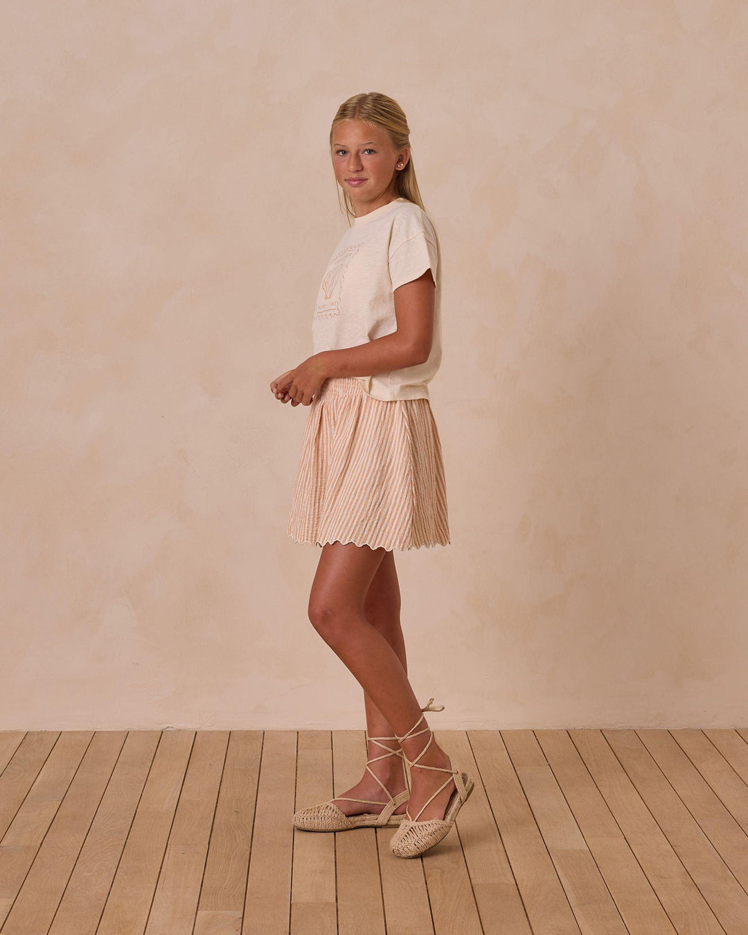 young girl modeling the boxy tee and turned to the side so you can see the length of the shirt. it hits below the waist. 