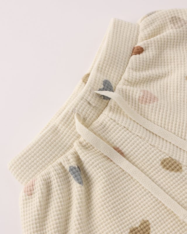 Beige textured fabric with small colorful patches on a light background