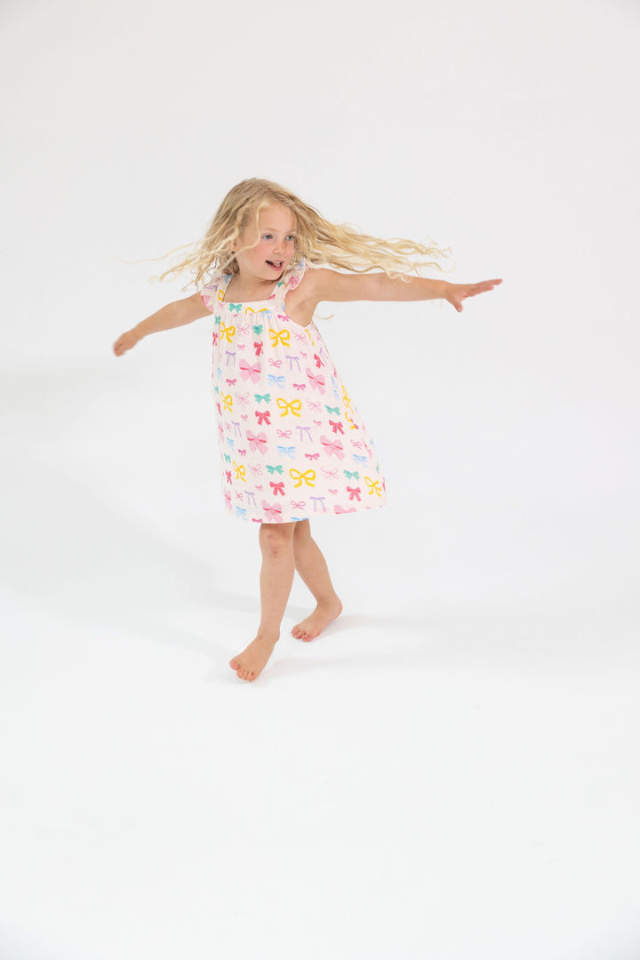 little girl twirling around so you can see the twirlability of this a-line silhouette. multi colored bow print all over it. 