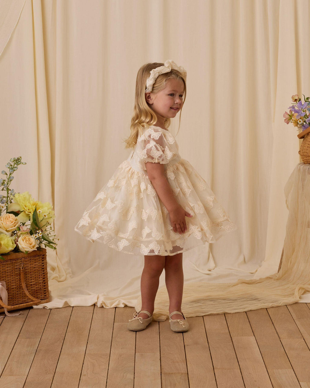 little girl modeling the ivory luna dress with dramatic sleeves and sheer butterlfy overlay. you can see the movement in this skirt in this picture