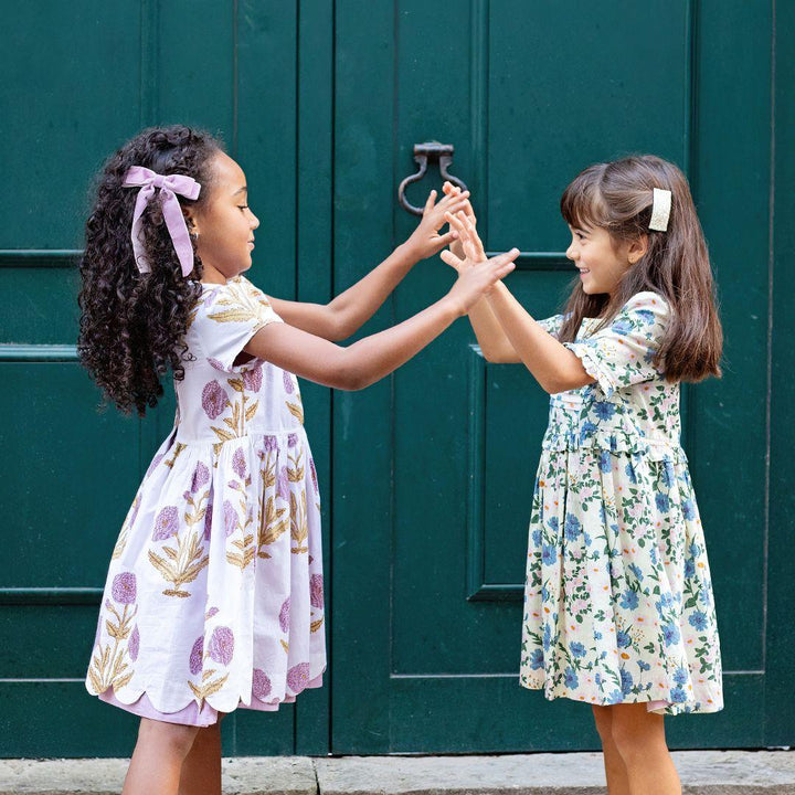 two girls playing and holding hands modeling floral dresses