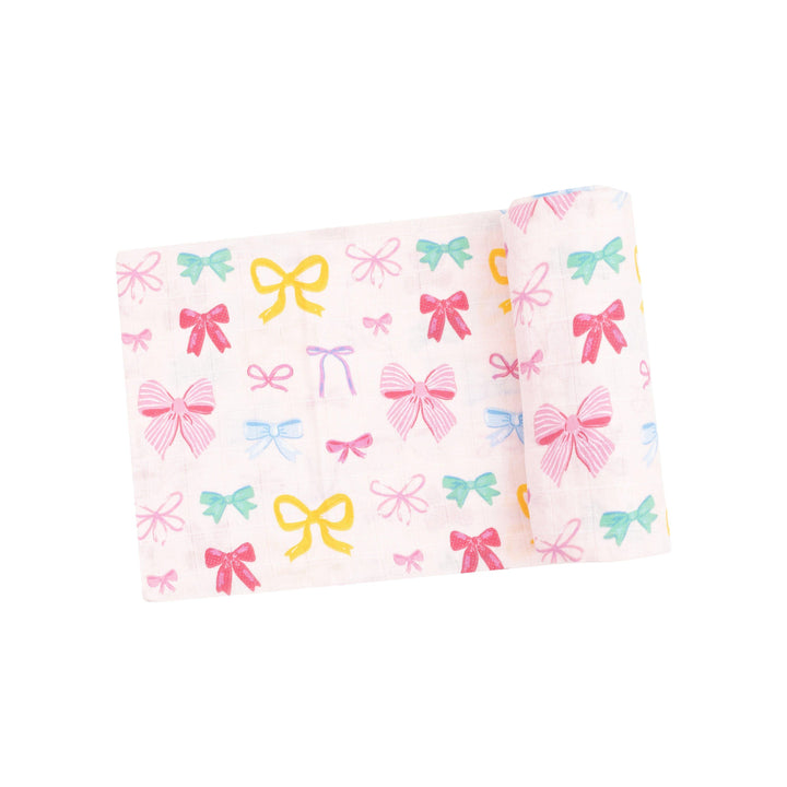 organic cotton muslin swaddle with multi colored bows all over: light pink, dark pink, yelllow and green bows. 