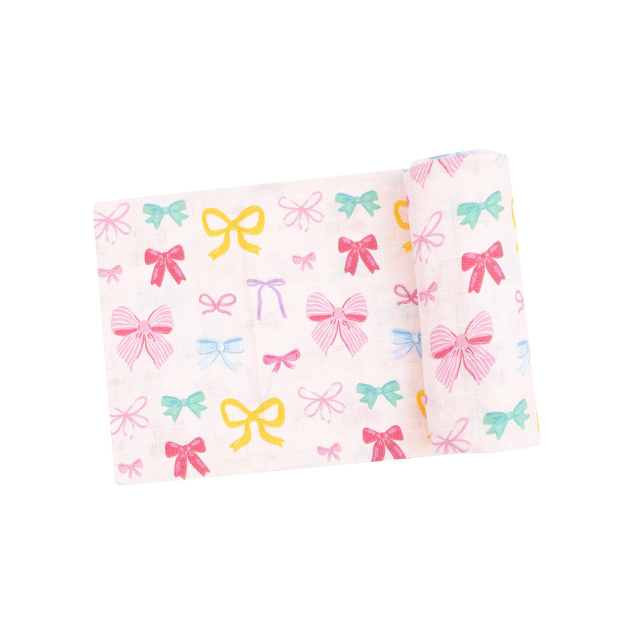 organic cotton muslin swaddle with multi colored bows all over: light pink, dark pink, yelllow and green bows. 