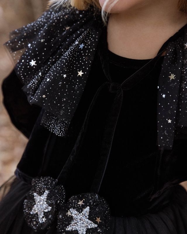 Black dress with star details worn by a person, with a blurred background