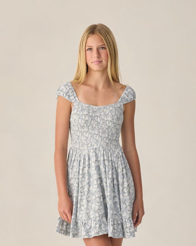 Woman wearing a light blue floral dress against a plain background