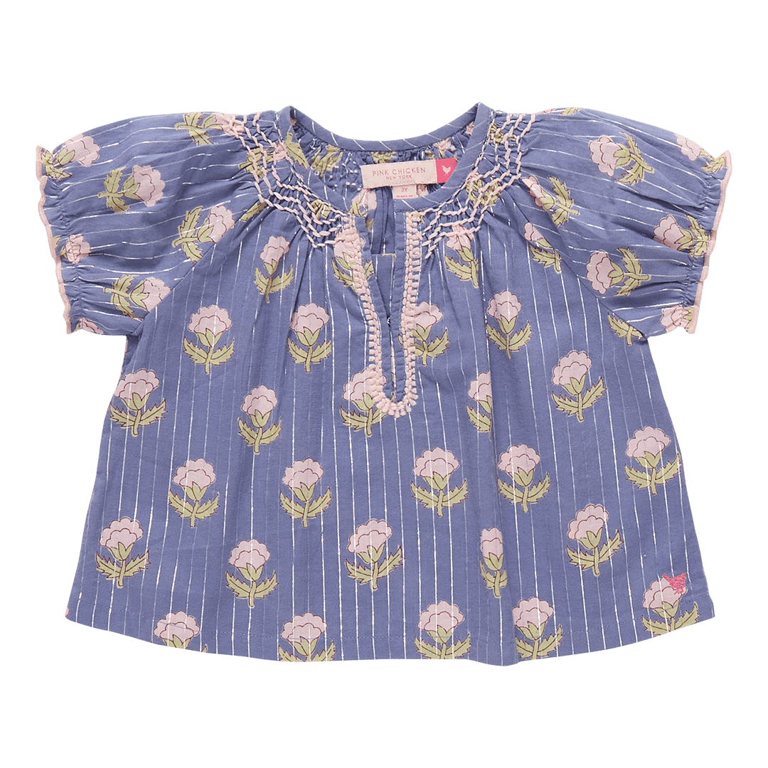 girls top with a notch in the top, blue base color with silver lurex running through it and light pink flowers and stitching on the edges. 