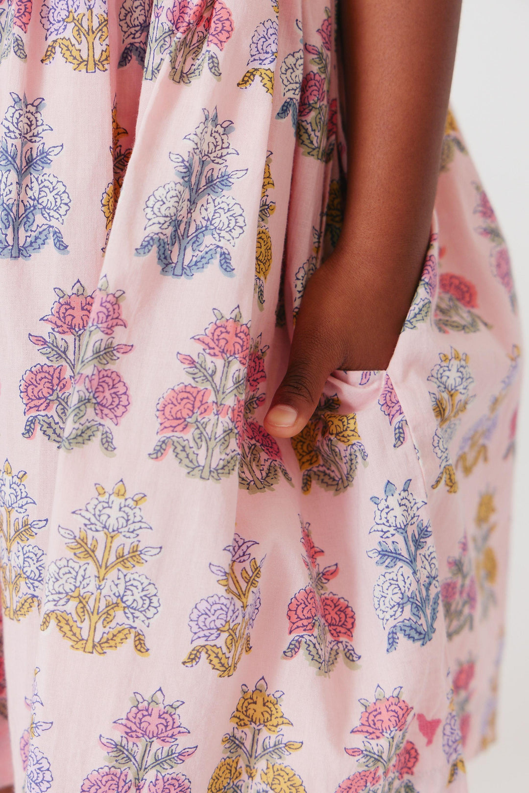 close up of the skirt, print and the hidden pockets in the skirt. the skirt is pink with bohemian florals in dark pink, blue and yellow. 