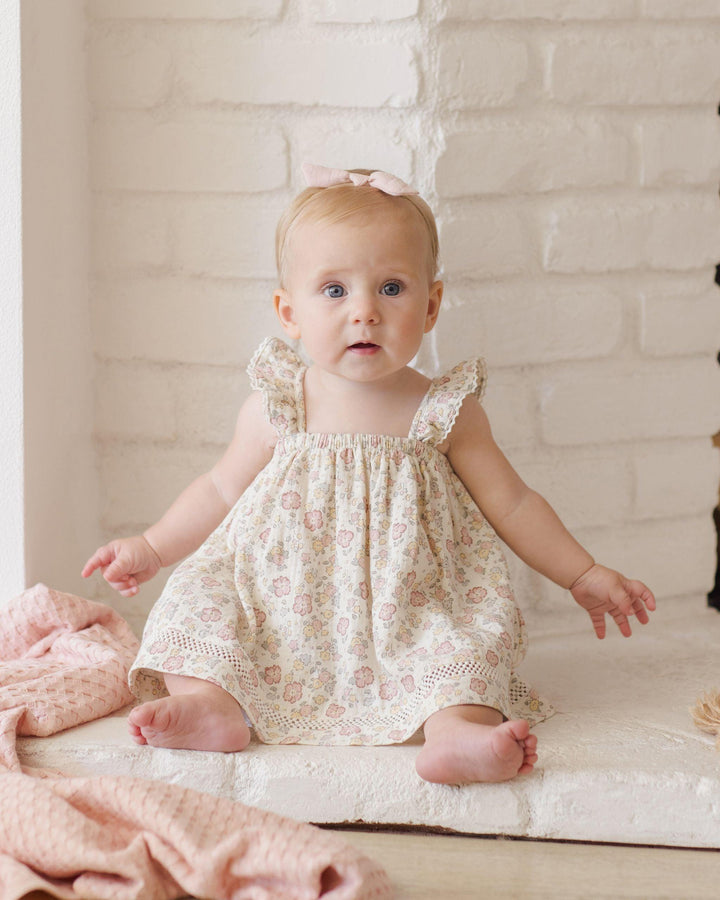 this picture shows a baby wearing the dress and how the sleeves look on the baby and where the dress hits the baby as she is sitting. the dress his mid leg while sitting and when standing would hit at the knee. 