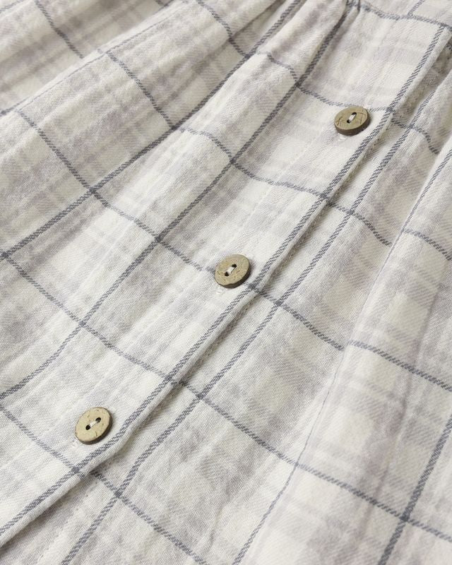 Close-up of a plaid fabric with buttons on a plain background