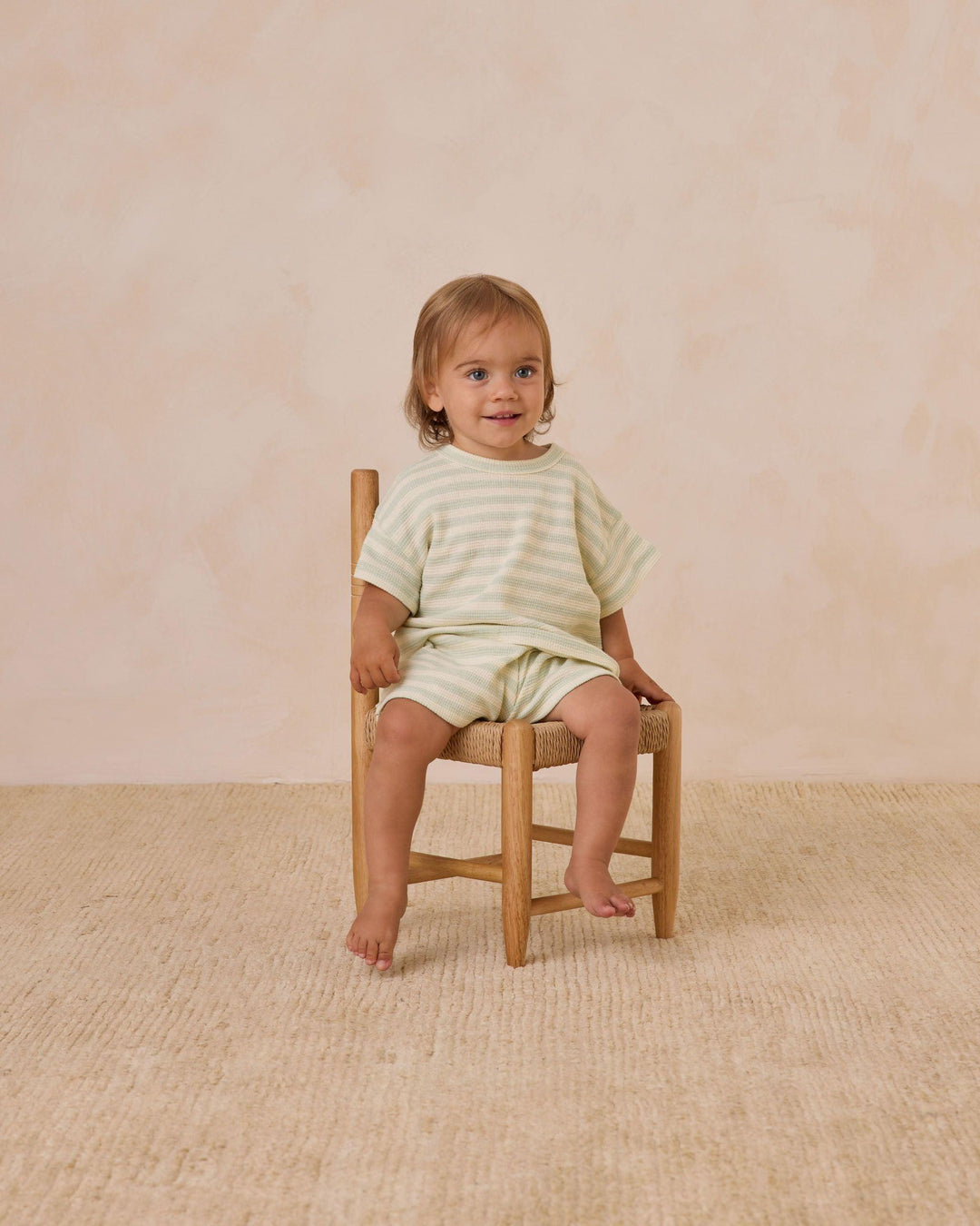 Little boy modeling the set and sitting on a chair. you can see where the shorts hit the little boy in this picture and how the length of the sleeves hit the elbow. 