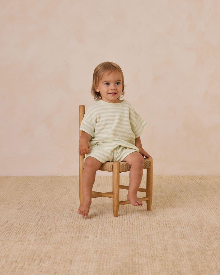 Little boy modeling the set and sitting on a chair. you can see where the shorts hit the little boy in this picture and how the length of the sleeves hit the elbow. 