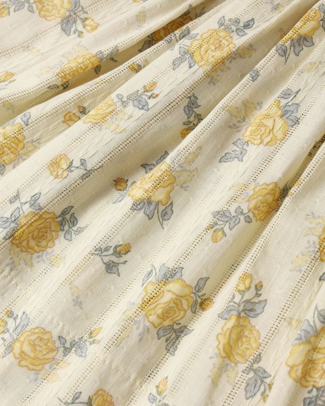 Close-up of floral fabric with yellow roses on a beige background