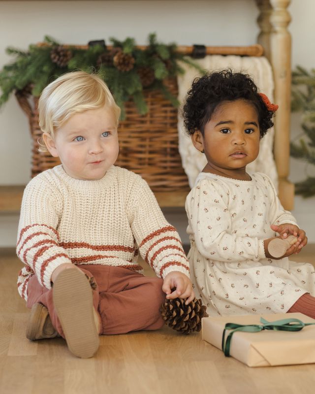 Two children sitting on the floor with a Christmas-themed background