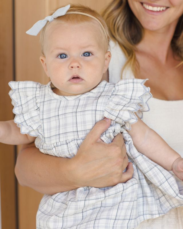 Baby in a checkered outfit held by a smiling woman