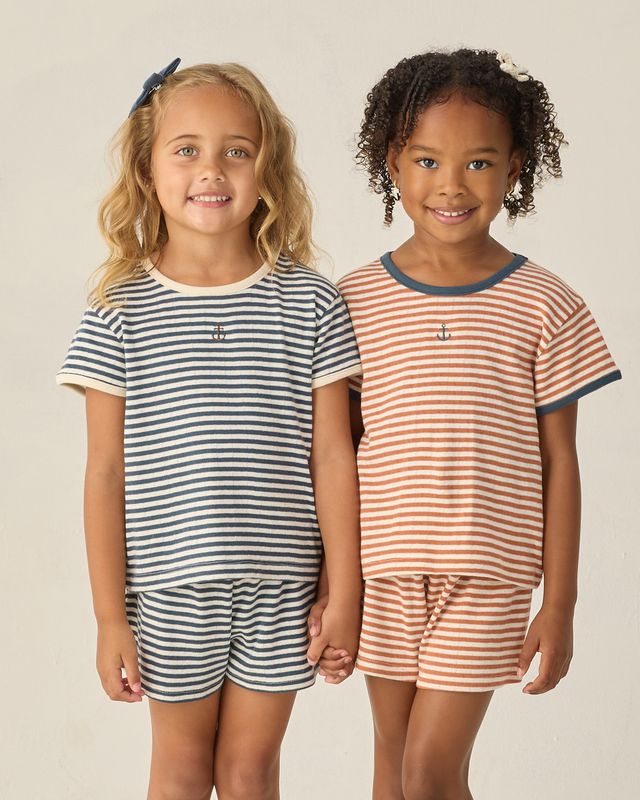 Two children wearing striped sets standing side by side against a plain background