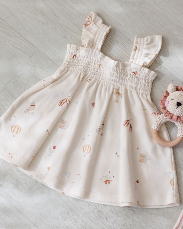 Baby dress with cartoon carnival pattern on a light wooden floor