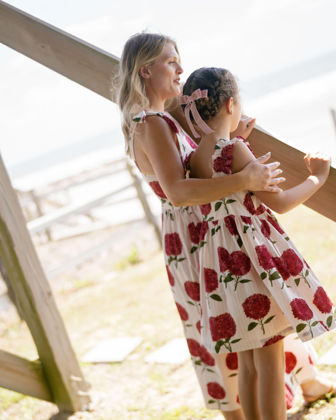 little girl wearing the pink hydrengea dress and looking out onto the beach from the back. matching mother moment. 