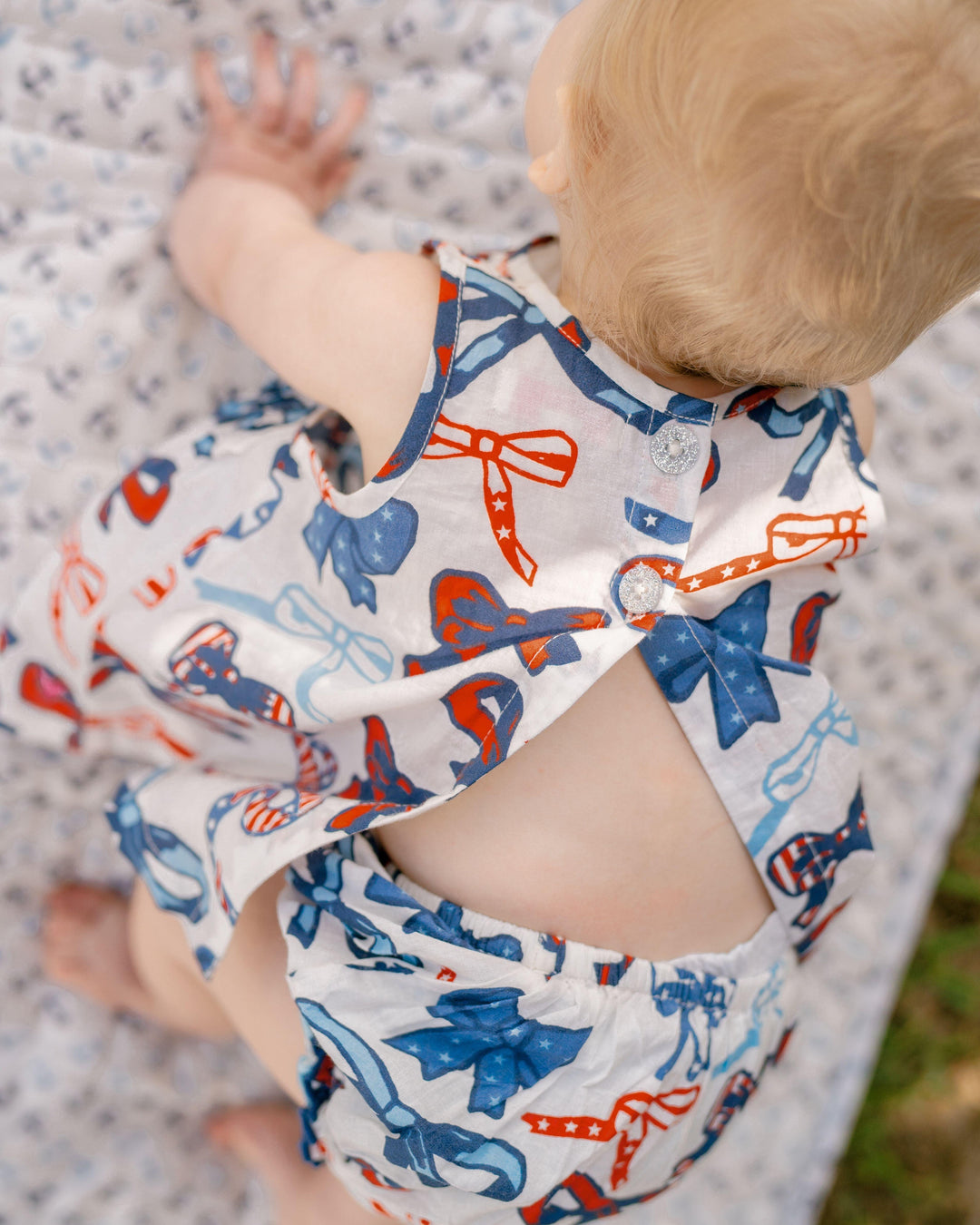 baby wearing red, white and bows outfit. the top has an open back for easy breathable wear on a hot day. 