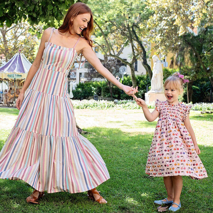 the little girl and her mom are dancing in the park each in pink chicken: one cherries dress and the mom in the maxi striped dress